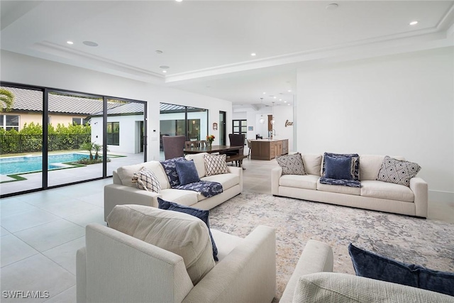 tiled living room featuring a tray ceiling and crown molding