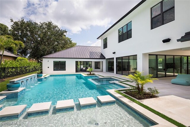 view of swimming pool featuring a patio area, pool water feature, and an in ground hot tub