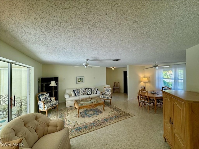 living room with ceiling fan and a textured ceiling