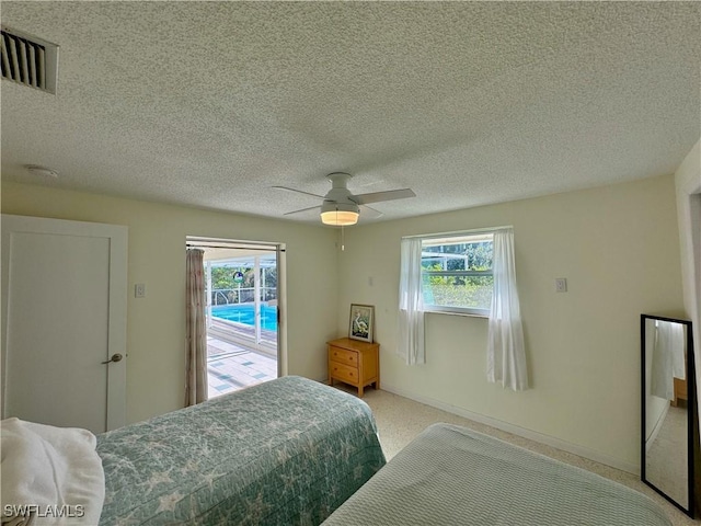 carpeted bedroom with ceiling fan, access to exterior, and a textured ceiling