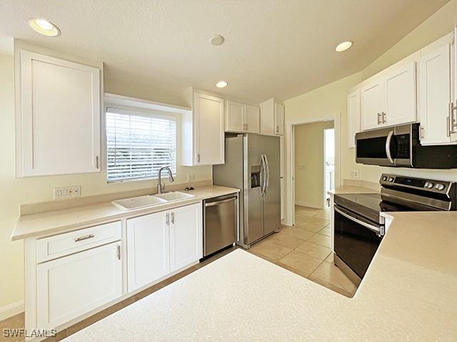 kitchen featuring white cabinets, appliances with stainless steel finishes, light tile patterned floors, and sink