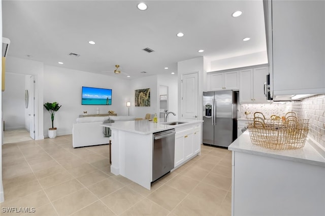 kitchen with sink, white cabinetry, stainless steel appliances, a kitchen island with sink, and backsplash