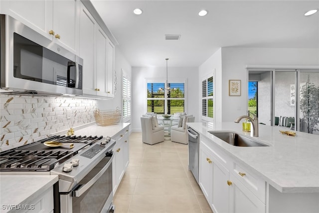 kitchen with hanging light fixtures, white cabinetry, appliances with stainless steel finishes, and sink