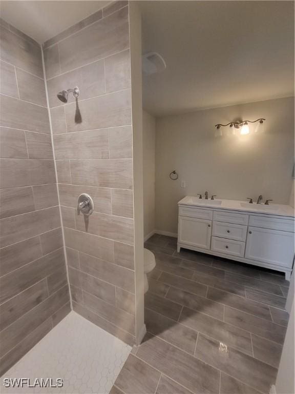 bathroom featuring vanity, toilet, and a tile shower