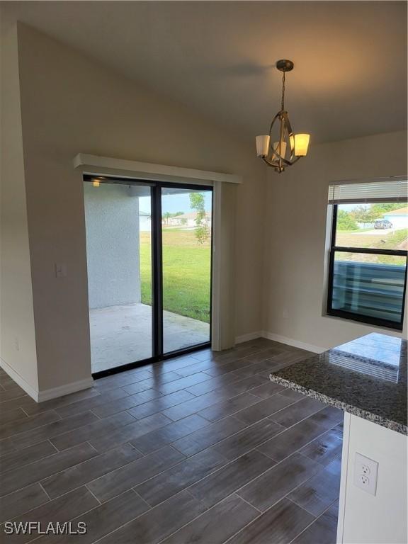 empty room with dark hardwood / wood-style flooring and a chandelier