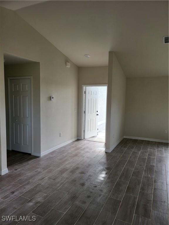 empty room featuring dark wood-type flooring and vaulted ceiling