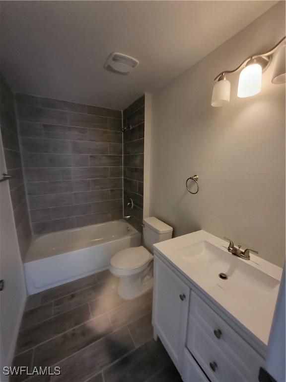 full bathroom featuring tiled shower / bath combo, toilet, and vanity