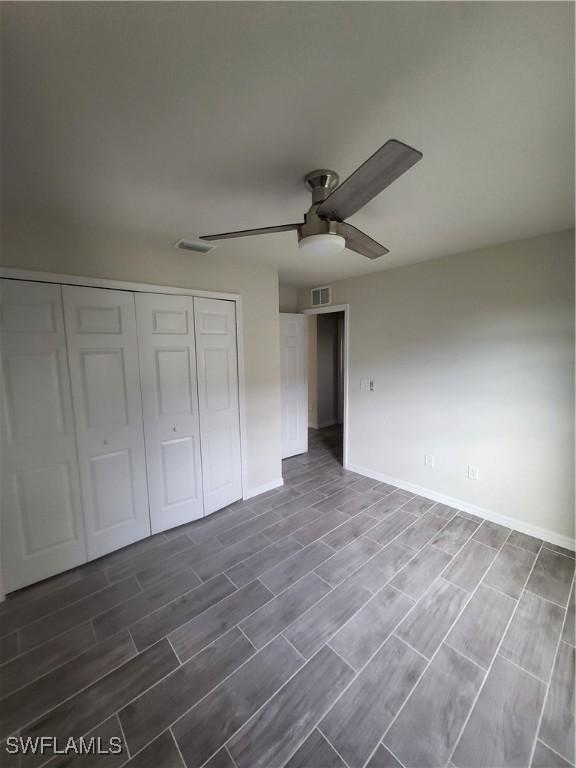 unfurnished bedroom with a closet, ceiling fan, and dark hardwood / wood-style flooring