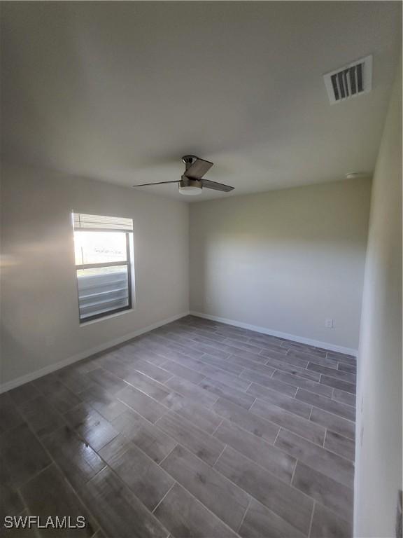 spare room with dark hardwood / wood-style floors and ceiling fan