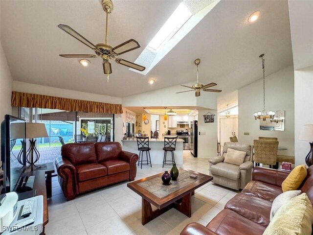 living room featuring ceiling fan with notable chandelier, light tile patterned floors, and a skylight