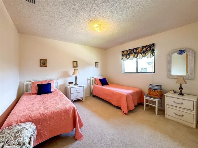 bedroom with light carpet and a textured ceiling