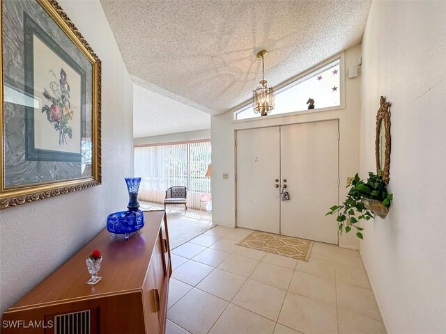 tiled entrance foyer featuring a textured ceiling and lofted ceiling