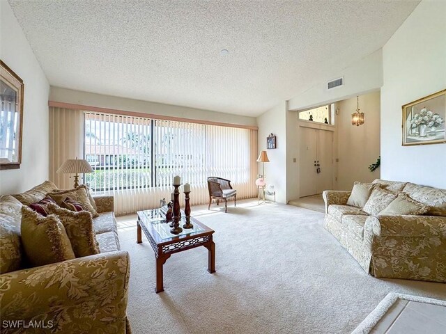 carpeted living room featuring vaulted ceiling, a textured ceiling, and an inviting chandelier