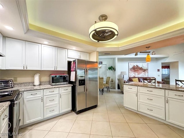 kitchen with a raised ceiling, light stone counters, white cabinets, and appliances with stainless steel finishes