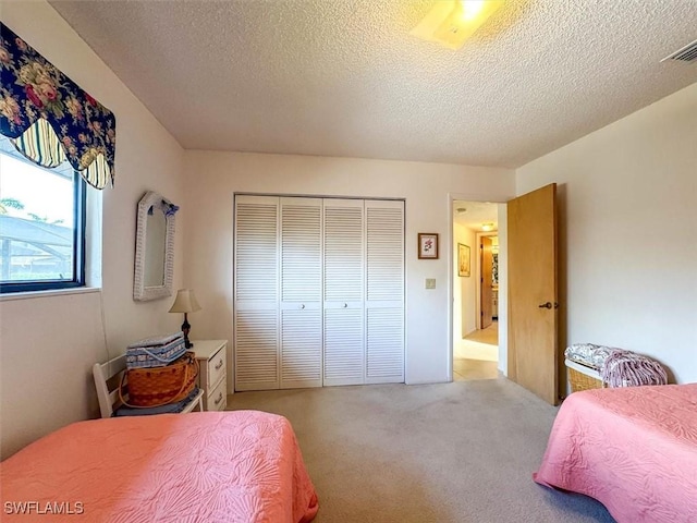 carpeted bedroom featuring a textured ceiling and a closet