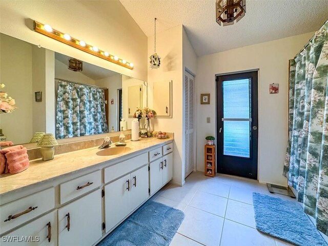 bathroom featuring tile patterned flooring, vanity, lofted ceiling, and a textured ceiling