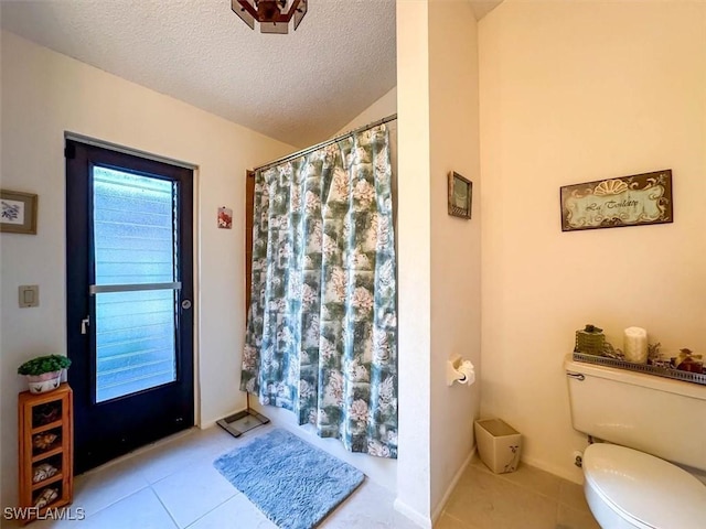 bathroom with tile patterned flooring, a textured ceiling, toilet, and a shower with shower curtain