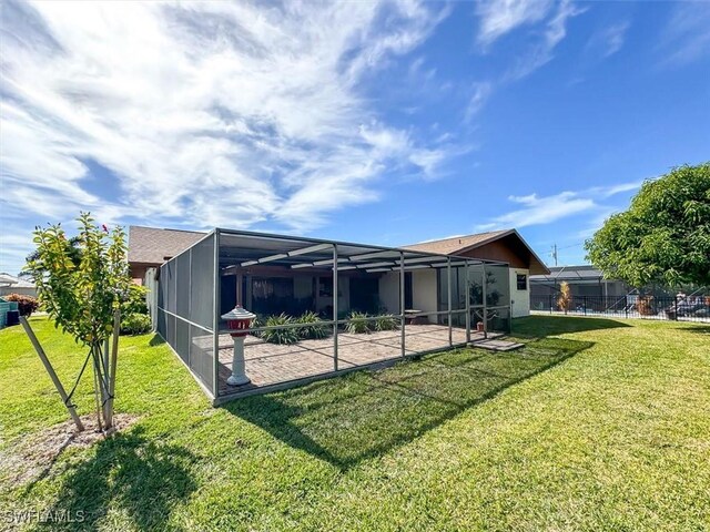 back of house featuring a yard, glass enclosure, and a patio area