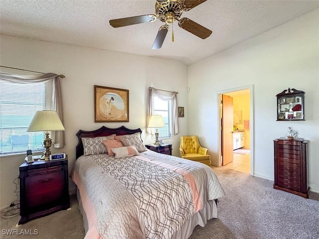 bedroom with light carpet, a textured ceiling, ceiling fan, and connected bathroom