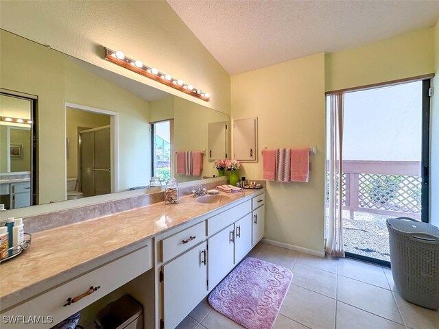 bathroom with tile patterned flooring, a textured ceiling, vaulted ceiling, a shower with door, and vanity