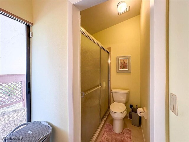 bathroom featuring tile patterned floors, toilet, and a shower with door