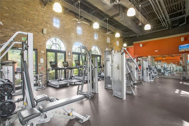 gym featuring brick wall and a high ceiling