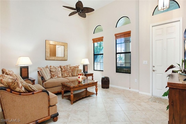 living room with ceiling fan, a towering ceiling, and light tile patterned floors