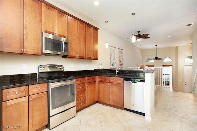 kitchen with kitchen peninsula, appliances with stainless steel finishes, dark stone counters, ceiling fan, and pendant lighting