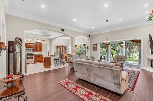 living room with dark wood-type flooring, ceiling fan, and ornamental molding