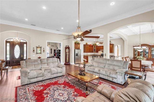 living room with ceiling fan, crown molding, wood-type flooring, and coffered ceiling