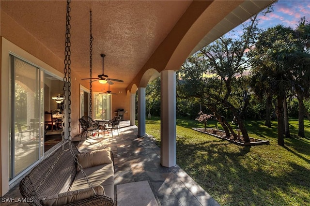 patio terrace at dusk with a yard and ceiling fan