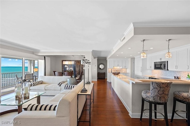 living room featuring a water view, crown molding, and dark wood-type flooring