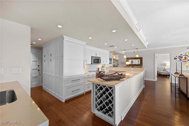 kitchen featuring backsplash, white cabinetry, crown molding, and dark wood-type flooring