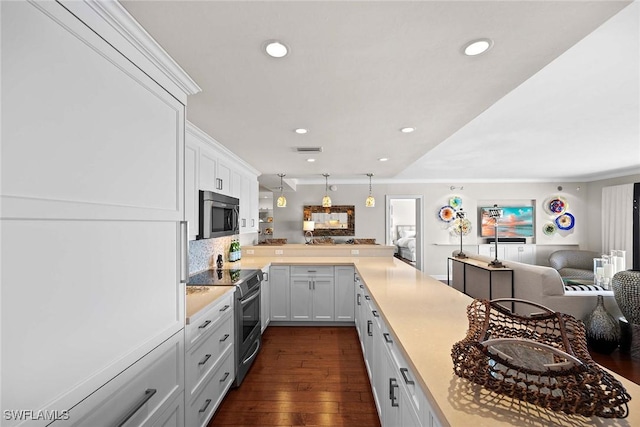 kitchen with white cabinetry, tasteful backsplash, dark hardwood / wood-style floors, kitchen peninsula, and appliances with stainless steel finishes