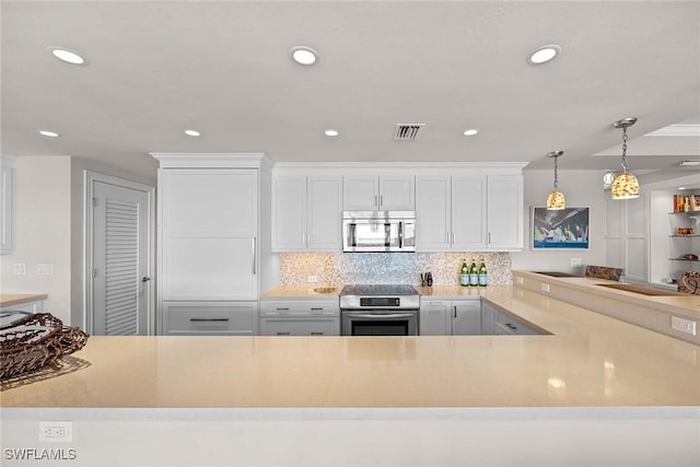 kitchen featuring tasteful backsplash, white cabinetry, stainless steel appliances, and decorative light fixtures