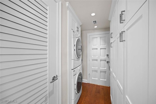 washroom featuring stacked washer / drying machine and dark hardwood / wood-style floors