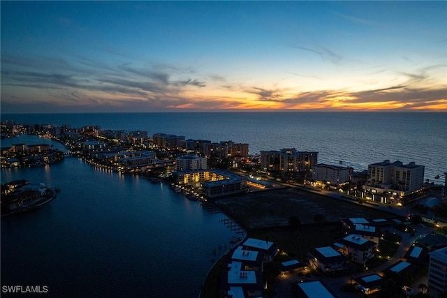 aerial view at dusk featuring a water view