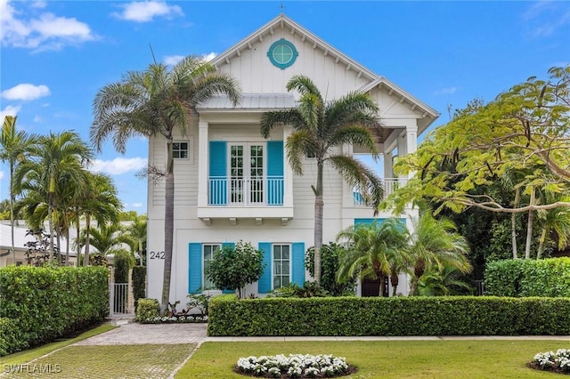 view of front of property featuring a front lawn, board and batten siding, and a balcony