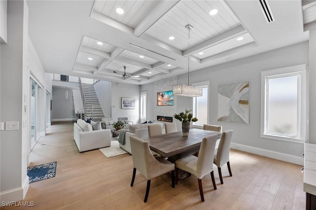 dining area with baseboards, coffered ceiling, stairway, light wood-type flooring, and a fireplace