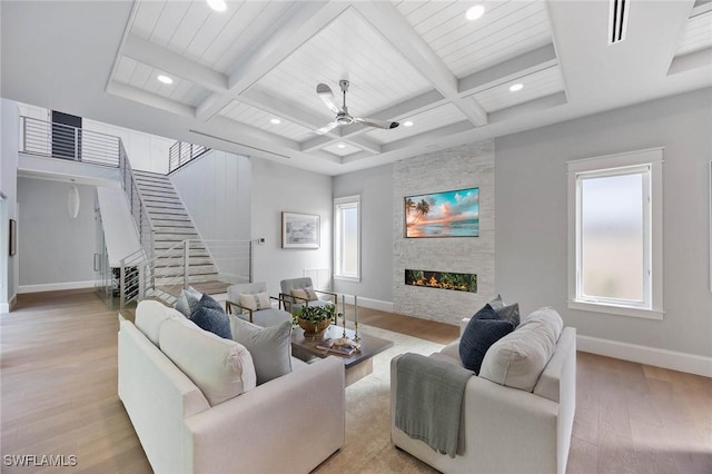 living area with light wood-type flooring, a fireplace, baseboards, and coffered ceiling