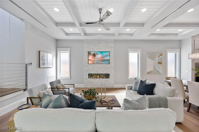 living room featuring light wood finished floors, baseboards, coffered ceiling, beamed ceiling, and a fireplace