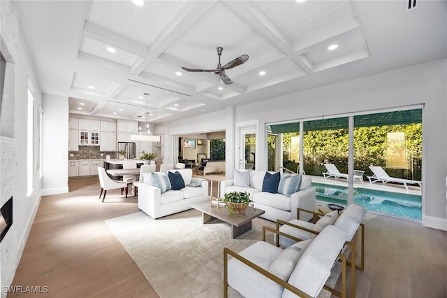 living area featuring beamed ceiling, coffered ceiling, and light wood-style flooring