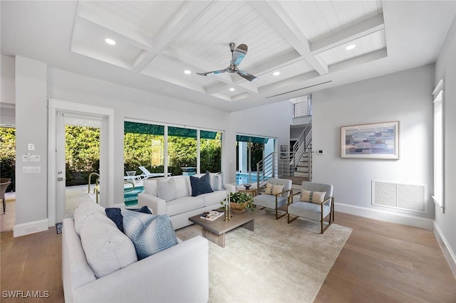 living room featuring coffered ceiling, visible vents, baseboards, and wood finished floors