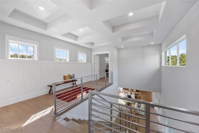 interior space with coffered ceiling, a wainscoted wall, an upstairs landing, a decorative wall, and recessed lighting