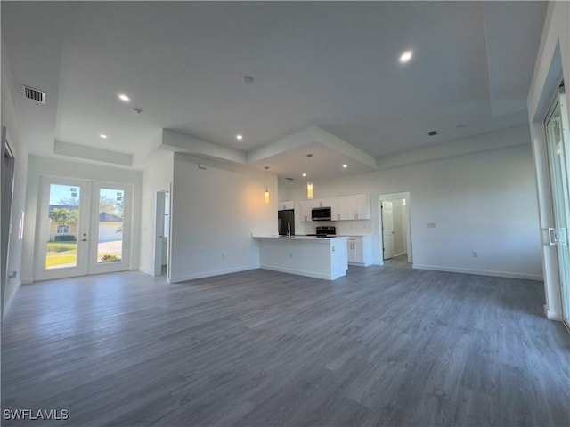 unfurnished living room featuring wood-type flooring, a raised ceiling, and french doors