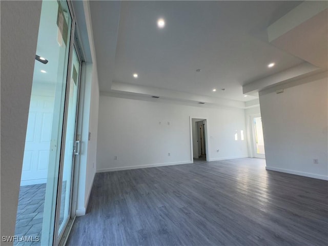 empty room with a tray ceiling and dark wood-type flooring