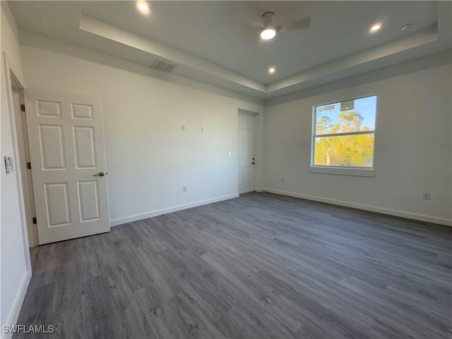 unfurnished room featuring dark hardwood / wood-style flooring, ceiling fan, and a tray ceiling