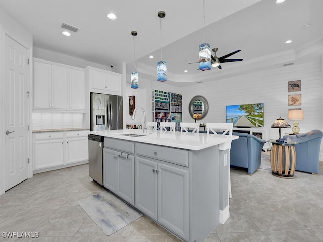 kitchen featuring pendant lighting, sink, ceiling fan, an island with sink, and appliances with stainless steel finishes