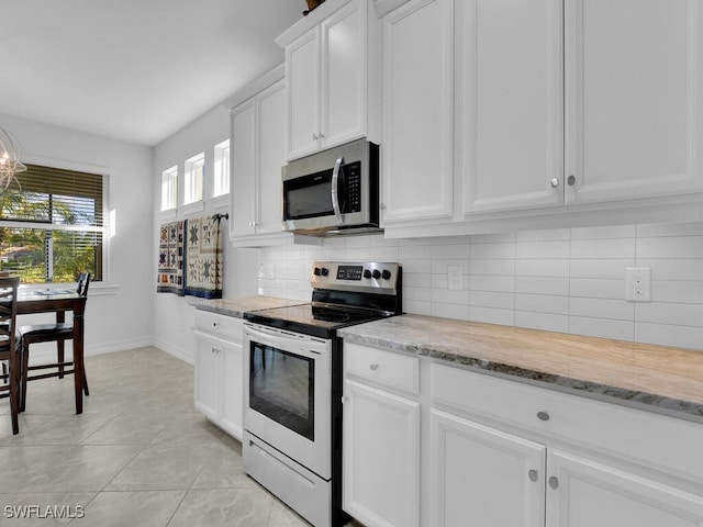 kitchen with decorative backsplash, light stone counters, stainless steel appliances, light tile patterned floors, and white cabinetry