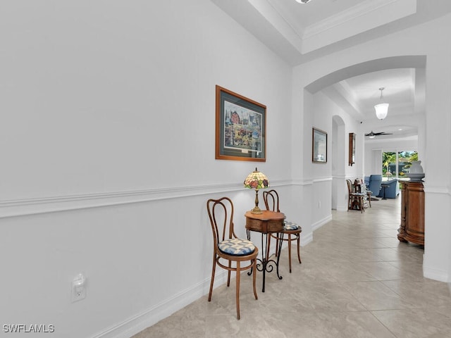 corridor featuring a tray ceiling, crown molding, and light tile patterned flooring